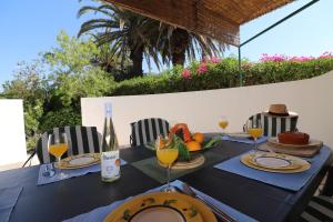 a table with a bottle of wine and a bowl of fruit at Villa Carvoeiro Ceu in Lagoa