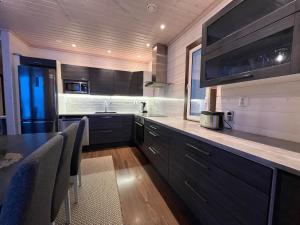 a kitchen with black cabinets and a table with chairs at Rantatähti Villa in Syöte