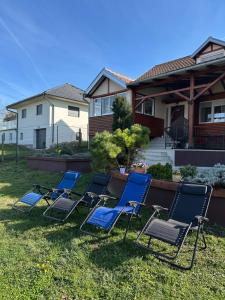 four chairs sitting in the grass in front of a house at Vikendica Dva labuda in Banoštor