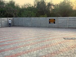 a person standing next to a fence with a sign at Hotel Marigold Vasad in Vāsad +4 photos
