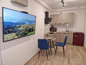 a kitchen with a table and chairs and a tv on the wall at Apartamenty Centrum Plac Wolności ApartHotel wyjątkowy in Kielce