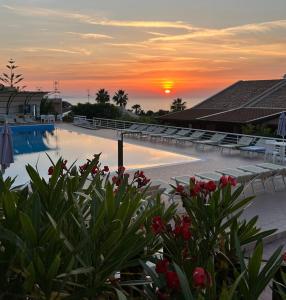 a pool with chairs and a sunset in the background at Divina Cefalù in Cefalù