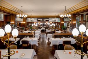 a restaurant with white tables and chairs and chandeliers at Hotel Schweizerhof Bern & Spa in Bern