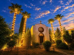 a church with christmas lights in front of palm trees at Tenuta del salento in Galatina