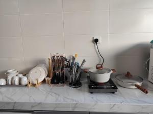 a kitchen counter with utensils and a pot on a stove at HeyFam Homestay in Sekinchan