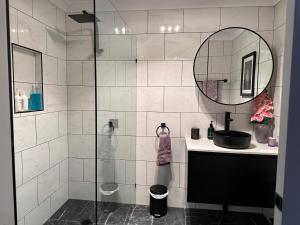 a bathroom with a shower with a sink and a mirror at Among The Trees Guest Suite in Kooralbyn +19 photos
