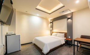 a hotel room with a white bed and a desk at Daily Motel in Incheon