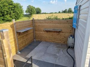 Ein hölzerner Sichtschutzzaun mit zwei Bänken auf einer Terrasse in der Unterkunft Petit logement tranquille in Wanchy-Capval