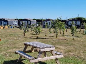 a wooden picnic table in a field with houses in the background at The Lighthouse Chalet in Leysdown-on-Sea