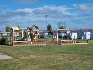 a park with two playground equipment in the grass at The Lighthouse Chalet in Leysdown-on-Sea