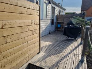 eine Holzterrasse mit Zaun neben einem Haus in der Unterkunft Petit logement tranquille in Wanchy-Capval