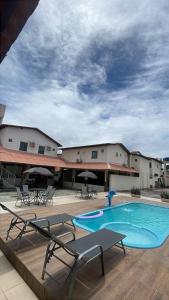 a hotel with a pool and tables and chairs at Pousada Brilho dos Lençóis in Barreirinhas