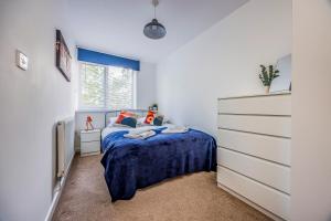 a bedroom with a blue bed and a dresser at Stylish Flat in the City Centre - Pass the Keys in Portsmouth