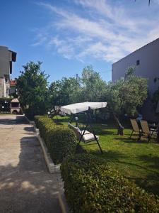 a park bench with a white umbrella in the grass at Elina House 2 in Nikiti