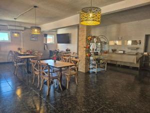 a dining room with tables and chairs and a kitchen at Hôtel Le Floreal in Trèbes