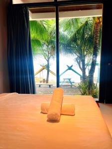 a bed with two towels on top of it with a window at Waikiki Lagi Beach in Ấp Tam Tân