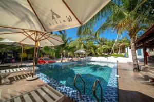 a swimming pool with chairs and an umbrella at Waikiki Lagi Beach in Ấp Tam Tân