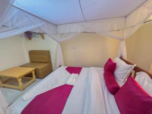 ein Schlafzimmer mit Himmelbett und Stuhl in der Unterkunft Miriito's Hotel in Kisii