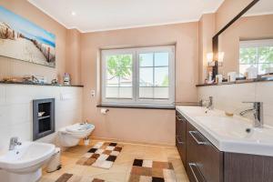 a bathroom with a sink and a toilet and a tub and a window at Ferienwohnung Auszeit am Meer in Koserow +20 photos