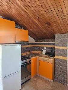 a kitchen with orange cabinets and a white refrigerator at Apartmani Banić Apartman 4 in Postira