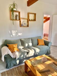 a living room with a green couch and a glass table at Maisonnette près du lac in Léon