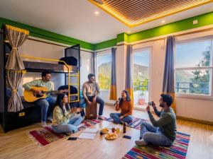 a group of people sitting in a living room playing music at The Hosteller Lansdowne in Lansdowne