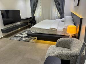 a bedroom with a bed and a tv and chairs at Reign Residence in Port Harcourt