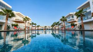 a large swimming pool with palm trees and buildings at Le Ramo - Résidence Ramoflores in Sidi Rahal