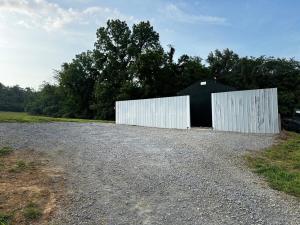 a black and white barn with a white door on a gravel road at Sunset in Hillsboro