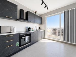 a kitchen with black cabinets and a large window at Prestigious & Modern SeaView Penthouse with Private Jacuzzi in Marsaskala