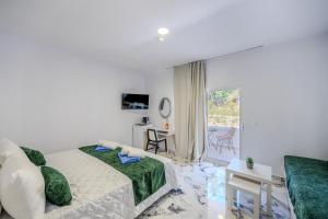 a white bedroom with a bed and a desk and a window at Bamboo Suites Hotel - Adults Only in Ialysos