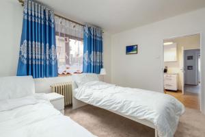 a bedroom with two beds and blue curtains at Byty Na vyhlídce in Zdice
