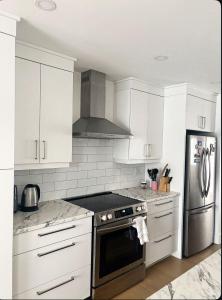 a kitchen with white cabinets and a stainless steel refrigerator at La perle de Dieppe in Dieppe