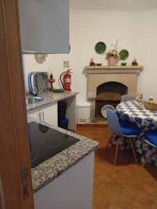 a kitchen with a sink and a table and a fireplace at Plantier Guesthouse in Figueira de Castelo Rodrigo