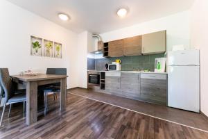 a kitchen with a wooden table and a white refrigerator at Nova City Apartments in Budapest