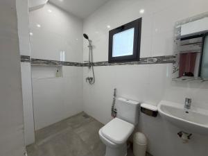 a white bathroom with a toilet and a sink at Le Welcome Almadies in Ngor