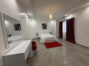 a white bedroom with a bed and a mirror at Le Welcome Almadies in Ngor