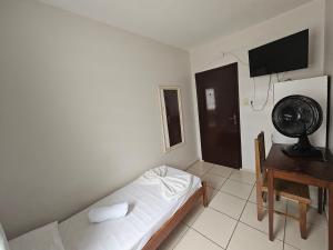 a room with a bed and a desk and a fan at Ok Inn Hotel Express in Tubarão