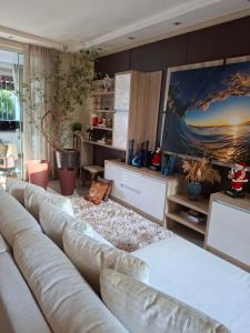a living room with a couch and a painting on the wall at confortável suite no jardim Botânico in Ribeirão Preto