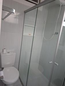 a bathroom with a toilet and a glass shower at confortável suite no jardim Botânico in Ribeirão Preto
