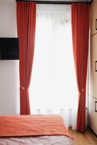 a bedroom with a window with red curtains at Numero Uno LUX in Sombor