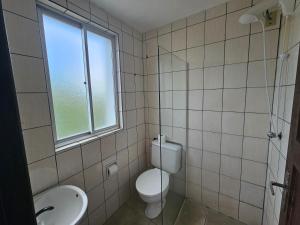 a bathroom with a toilet and a sink and a window at Ok Inn Hotel Express in Tubarão +47 photos
