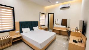 a bedroom with a bed and a desk and a television at Harsh Pushp Garden in Raipur