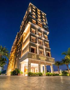 a tall building at night with palm trees in front at SKI - Sivakavi Iconic in Pondicherry