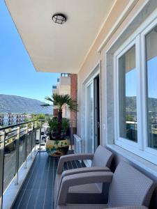 a balcony with two chairs and a plant on it at Quiet Cozy Apartment close to the beach in Velipojë