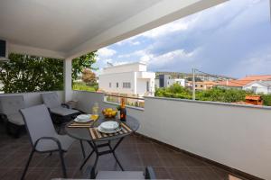 a patio with a table and chairs on a balcony at Apartments Milas in Okrug Gornji