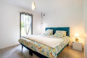 a bedroom with a bed with a blue headboard and a window at Villa Les Lodges Terre et Mer in Concarneau