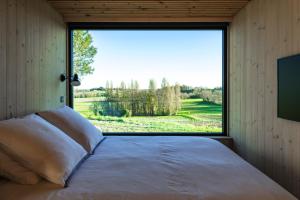 a bed in a room with a large window at Vineyard Cabins at Château Puynard in Berson +66 photos