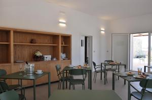 a dining room with tables and chairs and a kitchen at Dimora Thalèa - Retreat & Rooms in Nardò