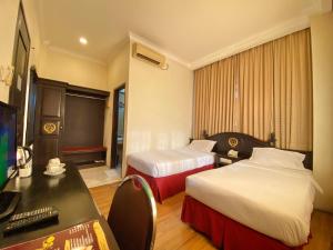 a hotel room with two beds and a desk at Quds Royal Hotel in Surabaya +12 photos